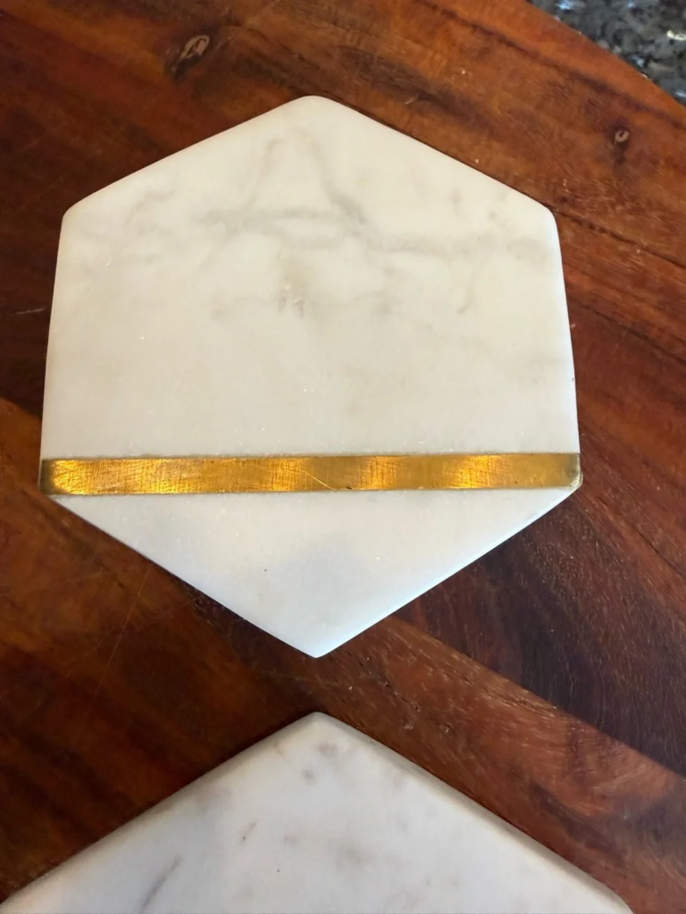 Hexagonal white marble coasters featuring a brass inlay design